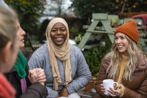 A group of women sit outside together having a hot drink and a chat